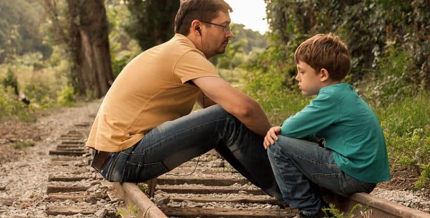 Father and son discussions are about something serious sitting on railroad tracks