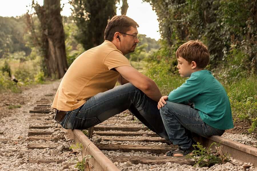 Father and son discussions are about something serious sitting on railroad tracks