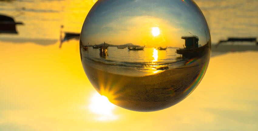 A ball where you can clearly see a beach with boats in the water with the rest of the image blurred