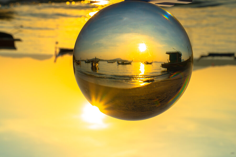 A ball where you can clearly see a beach with boats in the water with the rest of the image blurred