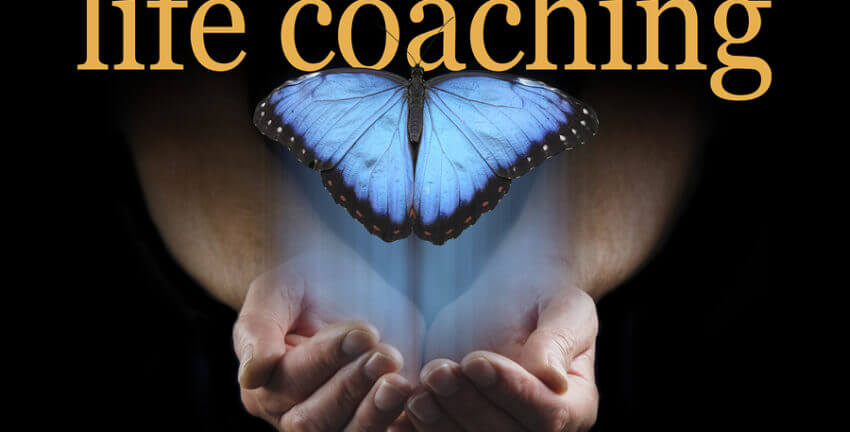 The word life coaching over a butterfly with hands cupping underneath the blue butterfly