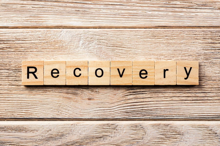 The word recovery on a wooden table with scrabble letters
