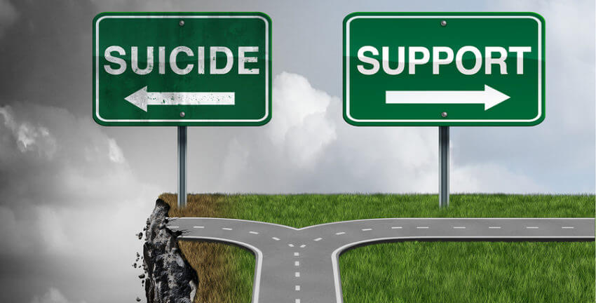 Two road signs with the words suicide over a cliff and the word support with a road